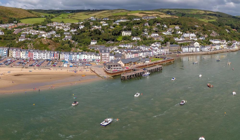 Aerial view of Aberdyfi's colourful sea front, beach, jetty and boats on the Dyfi estuary