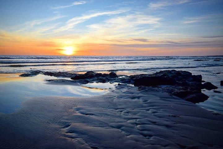 Sunset over the sea and rock pools on the beach at Tywyn